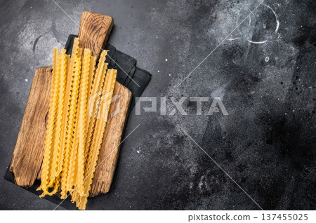 Uncooked mafaldine, ready to be transformed into a delicious dish that highlights its delightful texture. black background. top view 137455025