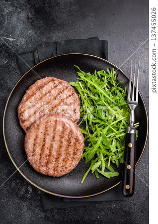 Grilled beef and pork meat patty paired with fresh veggies, an essential component for gourmet burgers. black background. top view Grilled beef and pork meat patty paired with fresh veggies, an essential component for gourmet burgers. black background. top view 137455026