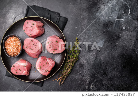 Tender fresh pork medallion, raw tenderloin meat perfect for elevating your dinner table with a touch of culinary finesse. black background. top view Tender fresh pork medallion, raw tenderloin meat perfect for elevating your dinner table with a touch of culinary finesse. black background. top view 137455057