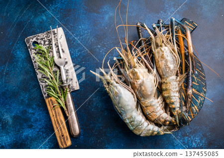 Uncooked rosenbergii fresh water shrimp ready for preparation, perfect for chefs looking to create exquisite seafood dishes. blue background. top view Uncooked rosenbergii fresh water shrimp ready for preparation, perfect for chefs looking to create exquisite seafood dishes. blue background. top view 137455085