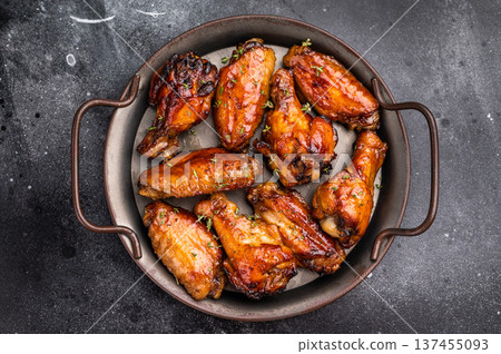 Savory grilled chicken wings smothered in tangy barbecue sauce, the ultimate treat for meat lovers and party enthusiasts. black background. top view 137455093