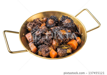 Braised beef oxtail stew with carrots and rosemary in pan on rustic wooden table, rich dark sauce and tender meat 137455121