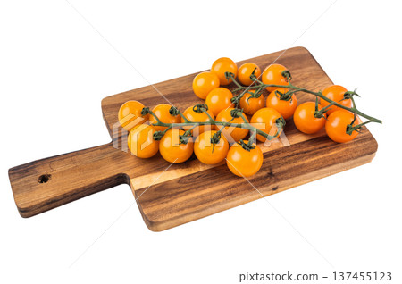 Yellow cherry tomatoes on vine on wooden cutting board isolated on white background, fresh organic produce for healthy cooking Yellow cherry tomatoes on vine on wooden cutting board isolated on white background, fresh organic produce for healthy cooking 137455123
