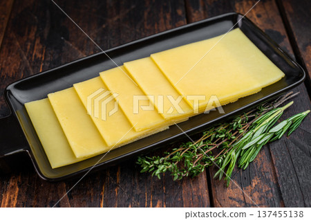 Stack of semi hard yellow cheese slices arranged on black tray, dairy ingredient on vintage wooden table background 137455138