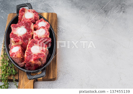 Raw beef oxtail pieces in cast iron skillet with thyme and rock salt, top view butcher style preparation for slow cooking Raw beef oxtail pieces in cast iron skillet with thyme and rock salt, top view butcher style preparation for slow cooking 137455139