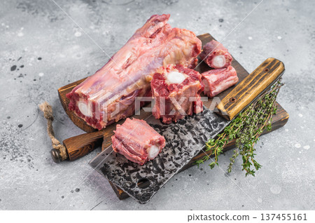 Raw beef oxtail pieces on wooden board with cleaver and thyme over light textured background with copy space Raw beef oxtail pieces on wooden board with cleaver and thyme over light textured background with copy space 137455161