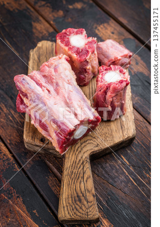 Butcher style raw Lamb oxtail segments with kitchen fork on rustic wooden table, traditional meat for stock and slow cooking 137455171