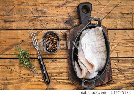 Raw pike perch fillets with skin in cast iron pan on rustic wooden table, fresh lean freshwater white fish with copy space. 137455173
