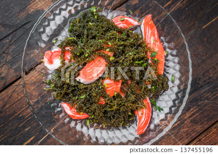 Sea grapes salad with imitation crab sticks on glass plate over dark wooden background Asian seafood dish top view Sea grapes salad with imitation crab sticks on glass plate over dark wooden background Asian seafood dish top view 137455196