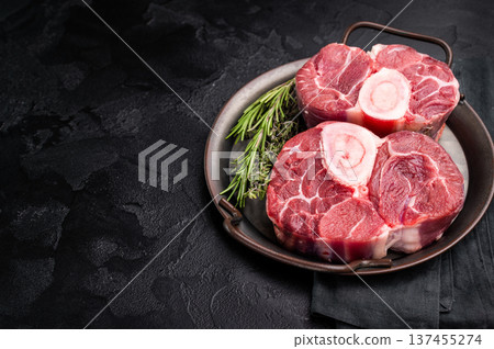 Freshly cross cut shank osso buco, ossobuco meat featuring succulent meat and bone marrow, waiting to elevate your cooking experience. black background. top view Freshly cross cut shank osso buco, ossobuco meat featuring succulent meat and bone marrow, waiting to elevate your cooking experience. black background. top view 137455274
