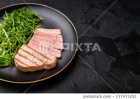 Succulent grilled tuna steak, showcasing vibrant color and rich taste, perfect for summer barbecues and elegant dinners. black background. top view Succulent grilled tuna steak, showcasing vibrant color and rich taste, perfect for summer barbecues and elegant dinners. black background. top view 137455281