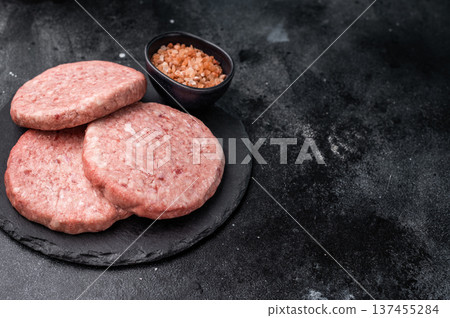Fresh raw beef meat patty ready for grilling, perfect for homemade burgers and delicious family meals.black background. top view Fresh raw beef meat patty ready for grilling, perfect for homemade burgers and delicious family meals.black background. top view 137455284
