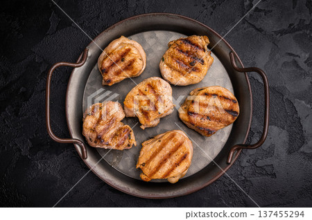 Flavorful grilled pork tenderloin cutlets, expertly cooked to perfection, promising a delicious dining experience. black background. top view Flavorful grilled pork tenderloin cutlets, expertly cooked to perfection, promising a delicious dining experience. black background. top view 137455294