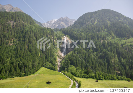 Alpine mountain waterfall flowing through green forest valley in scenic summer landscape Alpine mountain waterfall flowing through green forest valley in scenic summer landscape 137455347