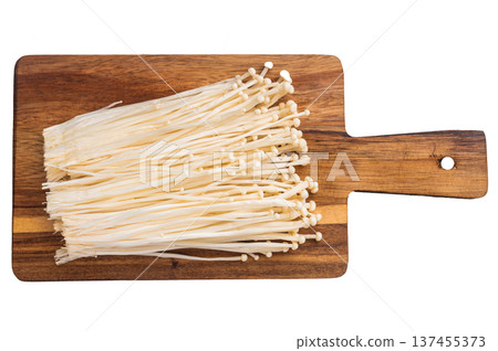 Fresh Enoki mushrooms placed on a wooden cutting board against a white background, ready for cooking Asian cuisine. Kitchen prep concept. Fresh Enoki mushrooms placed on a wooden cutting board against a white background, ready for cooking Asian cuisine. Kitchen prep concept. 137455373