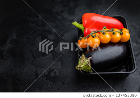 Top view of aubergine sweet pepper and cherry tomatoes in food packaging, healthy organic produce on dark surface Top view of aubergine sweet pepper and cherry tomatoes in food packaging, healthy organic produce on dark surface 137455380