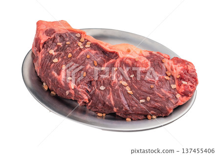 Raw marbled striploin steak with salt crystals on a metal plate over white background, premium beef cut ideal for gourmet cooking. 137455406