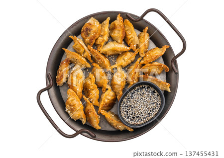 Fried gyoza potstickers with golden crust and sesame dip on a bright textured surface. Asian appetizer top view. Fried gyoza potstickers with golden crust and sesame dip on a bright textured surface. Asian appetizer top view. 137455431
