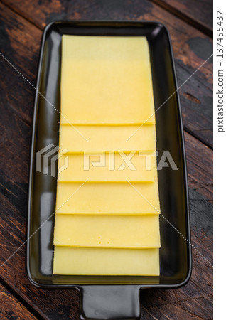 Stack of semi hard yellow cheese slices arranged on black tray, dairy ingredient on vintage wooden table background Stack of semi hard yellow cheese slices arranged on black tray, dairy ingredient on vintage wooden table background 137455437