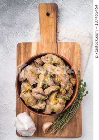 Tasty homemade chicken gizzards served with thyme and garlic on light concrete background ideal for culinary design. Tasty homemade chicken gizzards served with thyme and garlic on light concrete background ideal for culinary design. 137455454