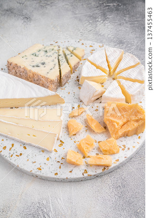 Brie Camembert Parmesan and Roquefort arranged on a terrazzo board against a textured light gray background for a bright gourmet look. Brie Camembert Parmesan and Roquefort arranged on a terrazzo board against a textured light gray background for a bright gourmet look. 137455463