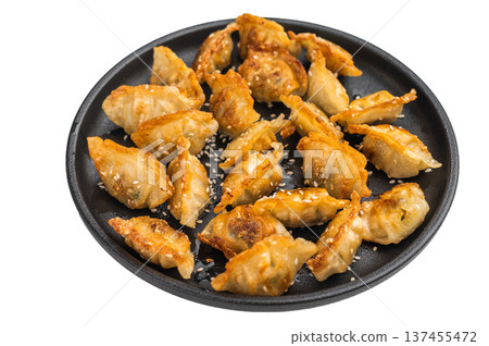 Crispy fried gyoza dumplings with sesame on a black plate over light background. Asian potstickers appetizer perfect for menu or food ads. 137455472