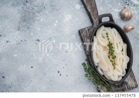 Fresh calamari rings in cast iron bowl with thyme on textured gray background ideal seafood ingredient for gourmet cooking. 137455478