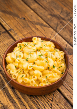 Creamy mac and cheese in a rustic bowl on a wooden table, garnished with fresh thyme, 137455480
