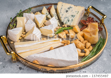 Assortment of Brie creamy Camembert and blue Roquefort served with nuts and fresh rosemary on a textured gray surface. 137455497