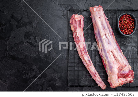 Raw beef oxtail segments on metal rack over dark textured background with copy space, butcher meat for broth and slow cooking 137455502