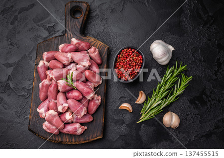 Fresh uncooked poultry duck hearts with herbs and garlic on rustic wooden board over dark textured background, gourmet ingredient. Fresh uncooked poultry duck hearts with herbs and garlic on rustic wooden board over dark textured background, gourmet ingredient. 137455515