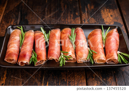 Delicious dry-cured Jamon pork meat served with herbs. Classic overhead view, perfect for a culinary theme. Delicious dry-cured Jamon pork meat served with herbs. Classic overhead view, perfect for a culinary theme. 137455520