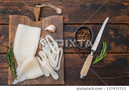 White fresh calamari ring displayed on rustic board with herbs ideal for seafood recipes menus and professional food photography. White fresh calamari ring displayed on rustic board with herbs ideal for seafood recipes menus and professional food photography. 137455531