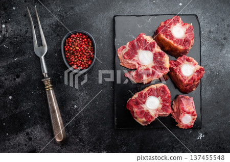 Butcher style raw oxtail pieces on dark slate board, traditional collagen rich meat for stock and slow cooking Butcher style raw oxtail pieces on dark slate board, traditional collagen rich meat for stock and slow cooking 137455548