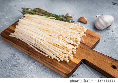 Cooking preparation flat lay Enoki fungi, fresh thyme, and garlic on a rustic board and modern concrete surface. Cooking preparation flat lay Enoki fungi, fresh thyme, and garlic on a rustic board and modern concrete surface. 137455553
