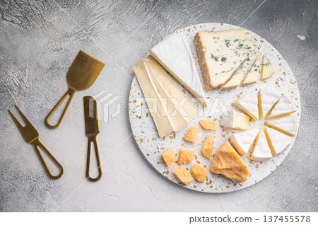 Brie Camembert Parmesan and Roquefort arranged on a terrazzo board against a textured light gray background for a bright gourmet look. 137455578