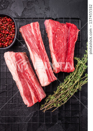 High-quality meat preparation. Raw beef cut with herbs and spices on a black textured background. Copy space provided. High-quality meat preparation. Raw beef cut with herbs and spices on a black textured background. Copy space provided. 137455582