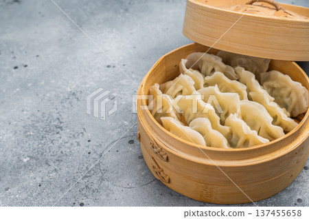 Steamed Asian dumplings mandu served in bamboo steamer on concrete background with chopsticks perfect for dim sum menus. Steamed Asian dumplings mandu served in bamboo steamer on concrete background with chopsticks perfect for dim sum menus. 137455658