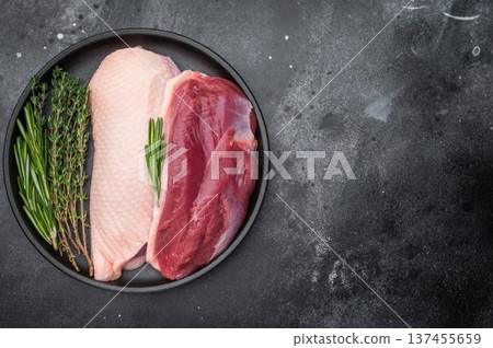 Plucked duck fillets with fresh herbs in dark plate on black background great for gourmet recipes cooking preparation and food stock content. 137455659