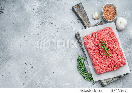 Fresh raw ground mince beef meat with rosemary on parchment over rustic wooden board and concrete background ideal for cooking and protein visuals. 137455673