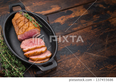 Juicy roasted duck breast whole and sliced in black pan with herbs perfect for culinary visuals and recipe content. Juicy roasted duck breast whole and sliced in black pan with herbs perfect for culinary visuals and recipe content. 137455686