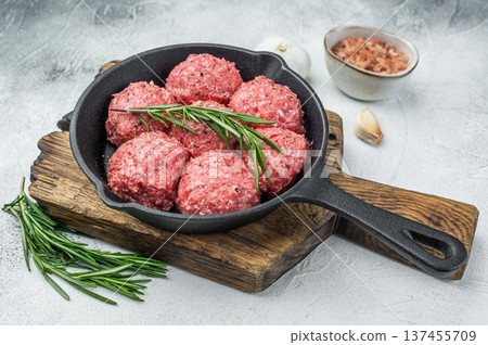 Uncooked raw meatballs Polpette style with garlic and salt in black skillet highlighting raw texture perfect for culinary and butcher visuals. Uncooked raw meatballs Polpette style with garlic and salt in black skillet highlighting raw texture perfect for culinary and butcher visuals. 137455709