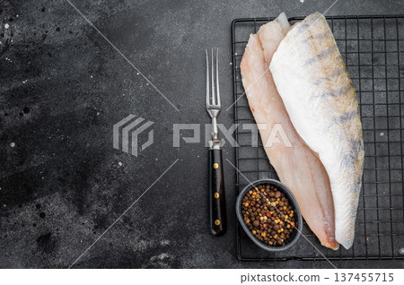 Raw pike perch fillets on dark background, one skin-on and one skinless, fresh freshwater white fish meat ready for cooking. 137455715