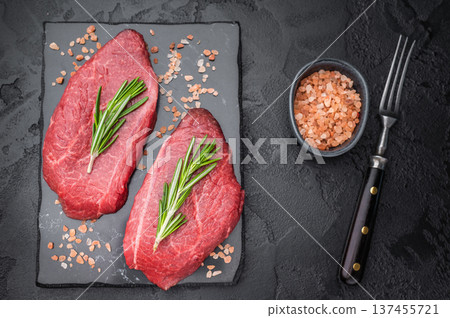 Marbled Wagyu beef chuck top blade steak similar to angus and yakiniku cuts displayed with rosemary on dark textured backdrop great for steakhouse food stock. 137455721