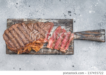 Dry aged New York striploin steak grilled to perfection with herbs and garlic on textured grey surface for culinary concepts. 137455722
