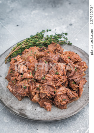 Tender slow cooked venison moose stew served on a grey plate with rustic texture, showcasing juicy shredded game meat and rich braised flavor. 137455724
