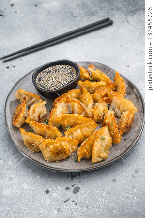 Golden fried dumplings gyoza with sesame seeds on gray tableware. Crunchy Asian potstickers shot top view on gray surface. 137455726