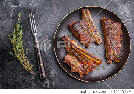 Gourmet glazed beef short ribs with fresh rosemary. Deep rusty brown background with ample negative space. 137455739