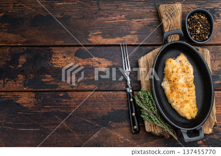Pan fried red snapper fillet in cast iron skillet on rustic wooden background with herbs and pepper. 137455770