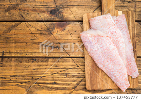 Raw redfish fillets on wooden cutting board. Fresh seafood ingredient on rustic wooden background with copy space. Raw redfish fillets on wooden cutting board. Fresh seafood ingredient on rustic wooden background with copy space. 137455777